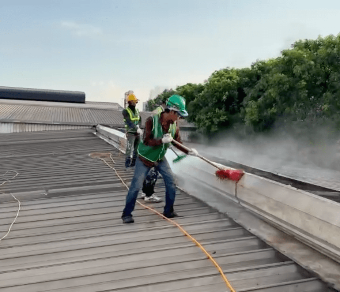 Công nhân vệ sinh mái tôn bằng máy phun áp lực cao trước khi sơn chống nóng