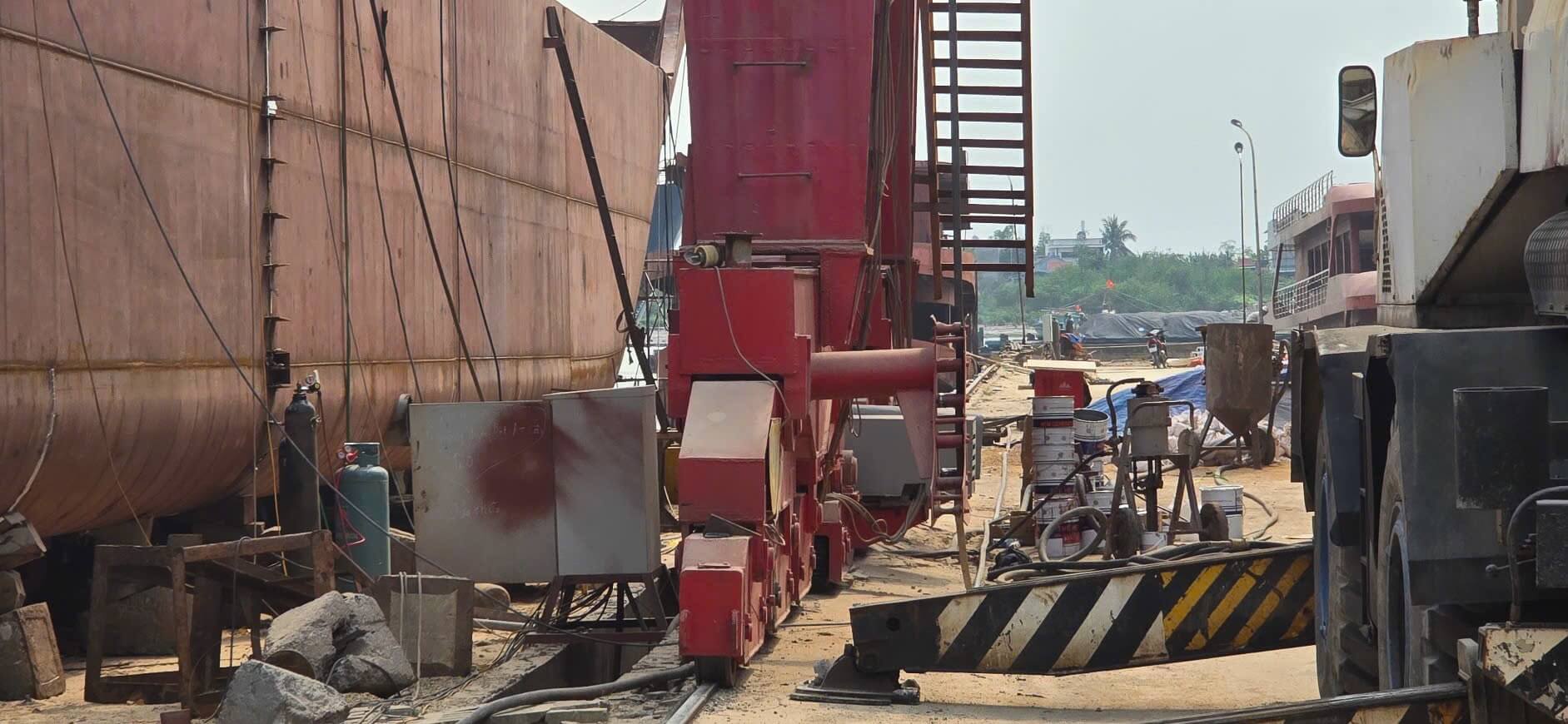 Thiết bị phun hạt làm sạch bề mặt và thùng sơn tập kết cạnh mạn tàu tại xưởng đóng tàu Quảng Yên
